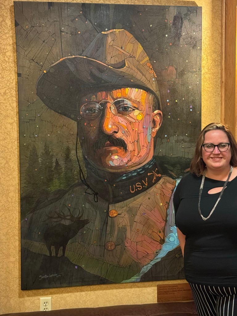 Kelli poses with a portrait of Teddy Roosevelt