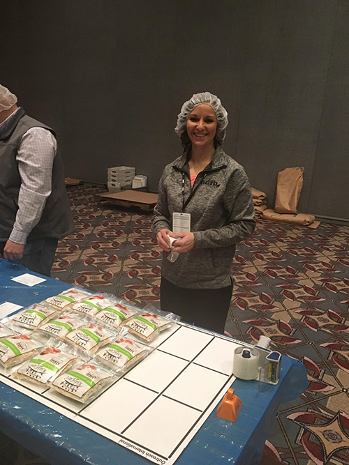 Carie participating in service project packing meals for hungry kids