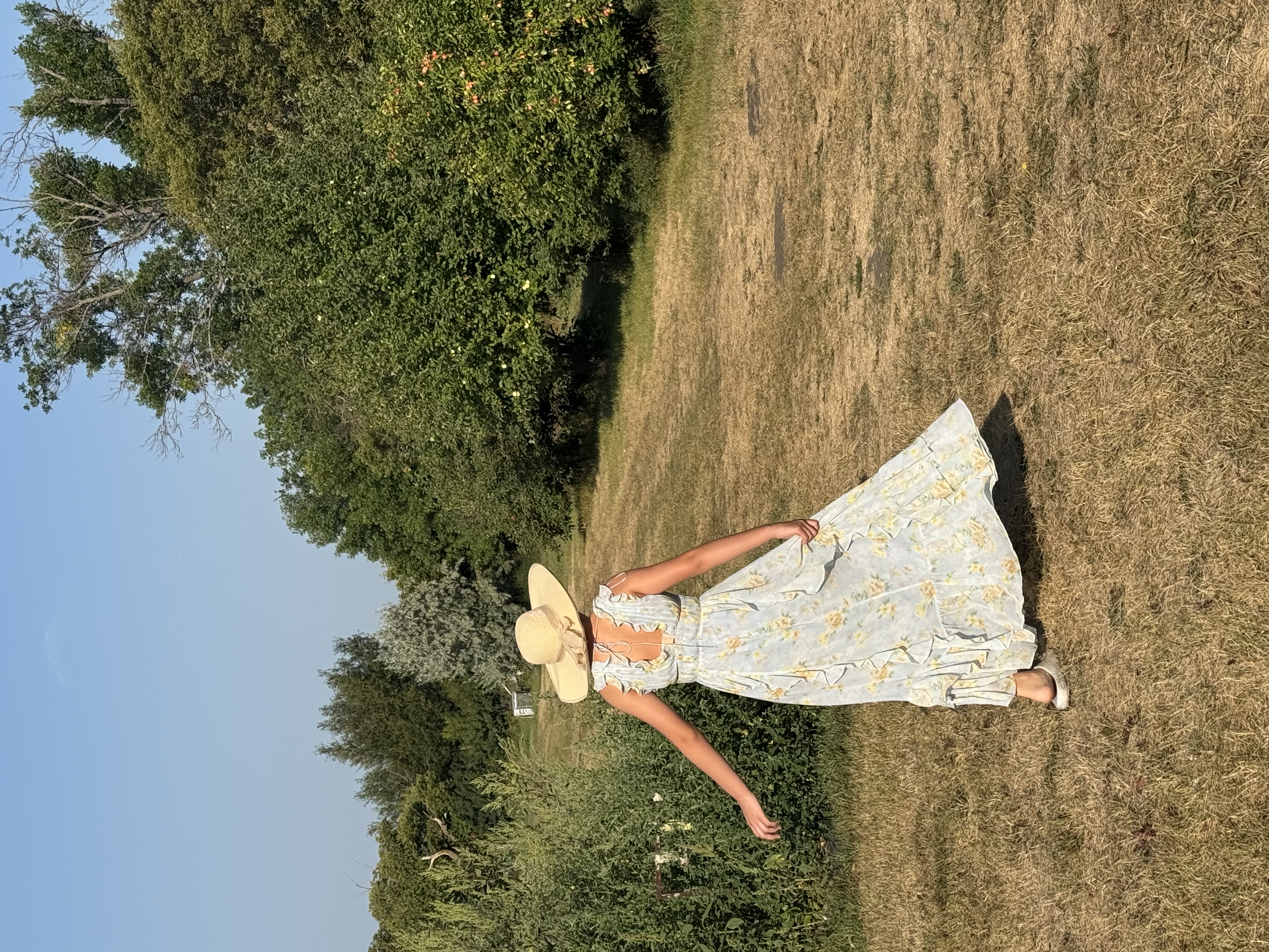 Miss E walks out to the orchard in a sundress and hat