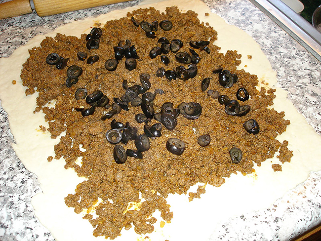 spreading the black olives over the meat mixture